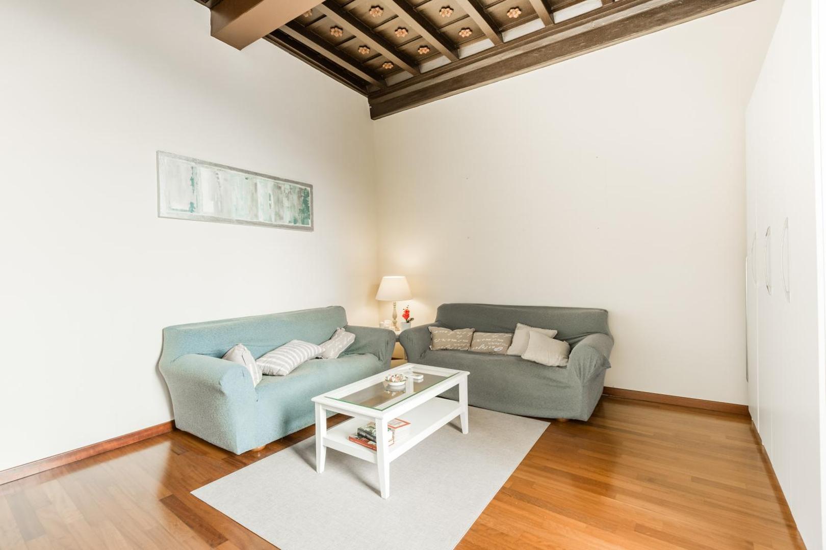 The living room of Navona Bernini Lodge, under its beamed ceiling