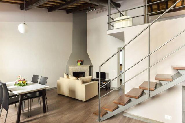 The living room of Navona Rubens Lodge, with dining table, fireplace and staircase